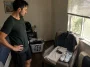 Man in a bedroom picking a polo shirt, chinos, and clean sneakers laid out as a golf-style summer outfit on a chair